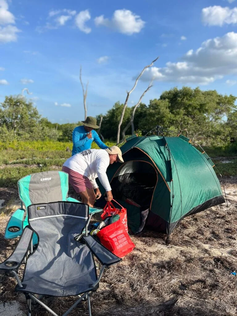Guía local arma el equipo de camping y la tienda en un campamento autorizado de Ría Lagartos.