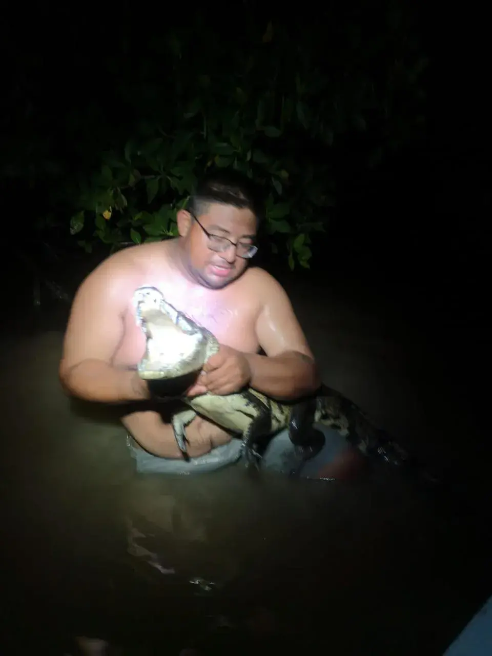 Guide holding a crocodile in the water